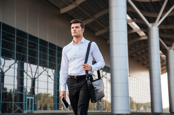 Portrait of a confident young businessman walking with pc tablet - Fotó, kép
