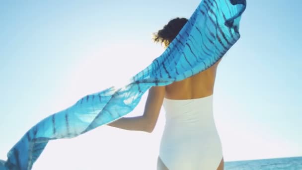 dziewczynę w strój kąpielowy chodzenie boso przez ocean - Materiał filmowy, wideo