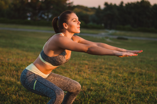 Atraktivní fitness žena cvičí v parku na trávě. SH - Fotografie, Obrázek
