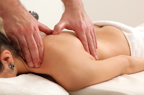 Masażysta robi masaż na kobiecym ciele w salonie spa. - Zdjęcie, obraz