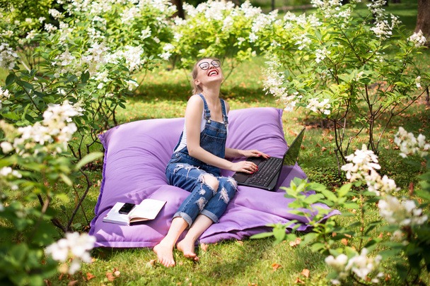 Pracuje na volné noze na zahradě. Psaní, surfování na internetu. Mladá žena odpočívá a baví se v parku. Dálkové vzdělávání, koncepce volného pohybu. - Fotografie, Obrázek