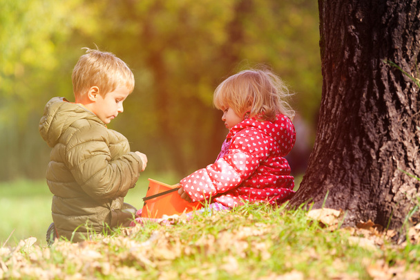 Kleine Jungen und Mädchen spielen im Herbst mit Blättern - Foto, Bild