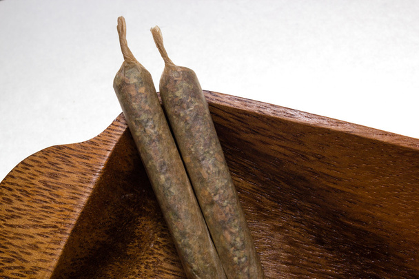 Χρηματιστήριο της χέρι έκανε μαριχουάνα αρθρώσεις σε ξύλινη πιατέλα - Φωτογραφία, εικόνα