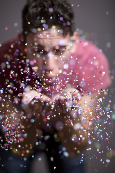Festive young man throwing confetti  - Foto, afbeelding