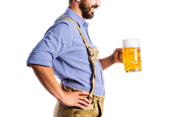 Unrecognizable man in bavarian clothes holding mug of beer - 写真・画像