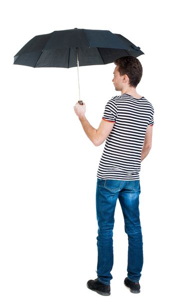 Back view of man in jeans under an umbrella. - Foto, Imagem