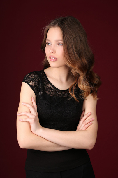 Miss with crossed arms. Close up. Dark red background - Фото, изображение