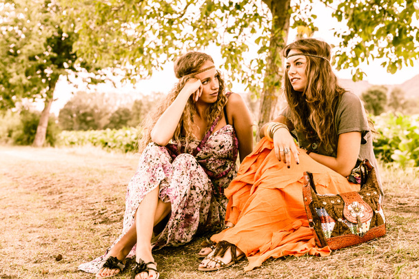 Beautiful hippie girlfriends sitting on grass  - 写真・画像
