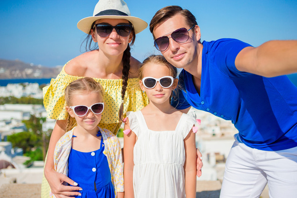 Familienurlaub in Europa. Eltern und Kinder beim Selfie im Hintergrund der Stadt Mykonos in Griechenland - Foto, Bild