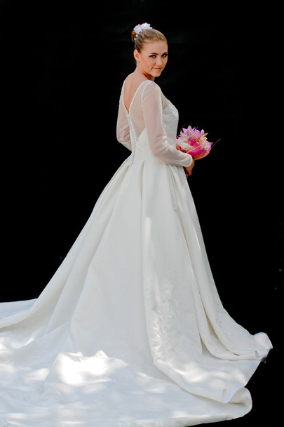Young beautiful bride looking over shoulder on black background - Foto, imagen