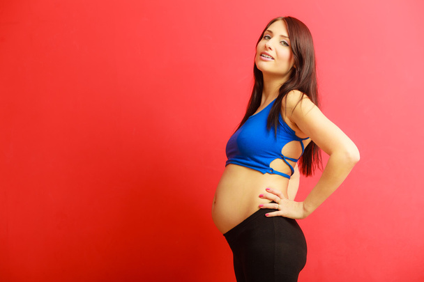 Long hair fit pregnant woman on red - Foto, Bild