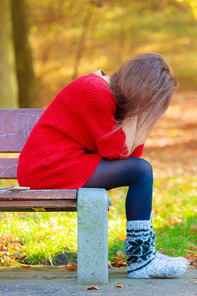 Sad woman sitting on bench in park - Фото, изображение