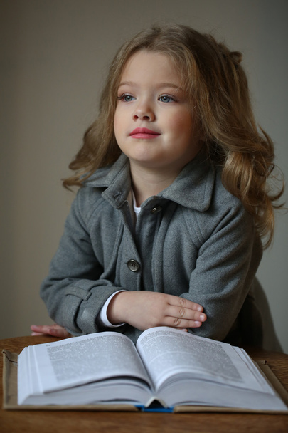 Child girl with a book. Close up. Gray background - Photo, Image