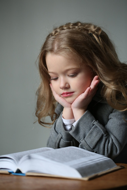 Kid reading a book. Close up. Gray background - Фото, изображение