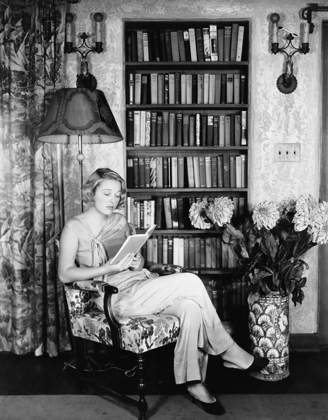 Fiatal nő olvasás a könyvtárban - Fotó, kép
