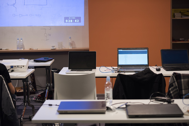 aula de TI vacía con código de programa en la pantalla del proyector y computadoras portátiles modernas en la mesa
 - Foto, Imagen