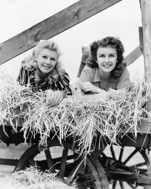 2 人の女性が足を空気中で干し草の馬車で横になっています。 - 写真・画像
