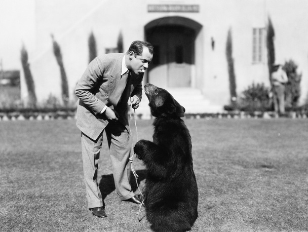 Mann füttert einen Bären, der auf seinem Rasen steht - Foto, Bild