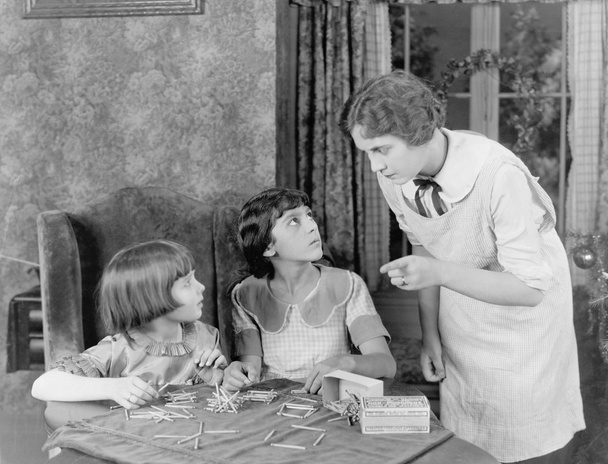 Woman scolding her two daughters for playing with matchsticks - Photo, Image