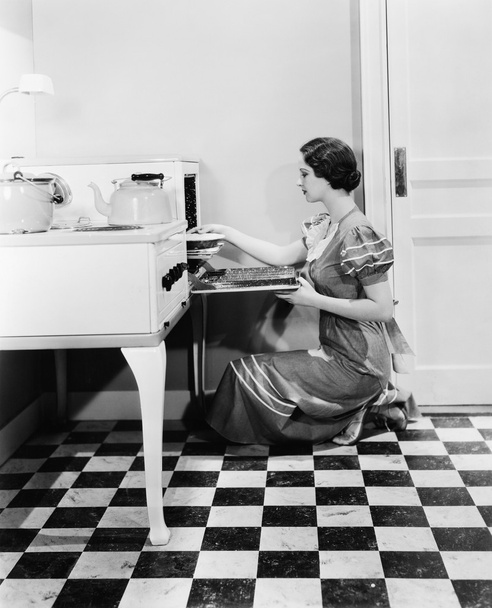 Profiel van een jonge vrouw die een taart ingebruikneming een oven - Foto, afbeelding