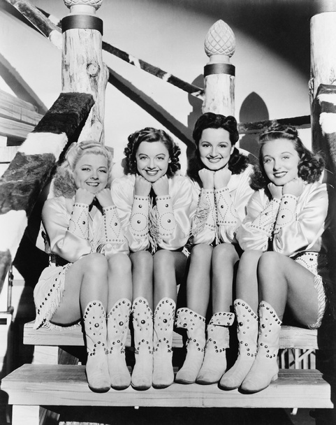 portret czterech młodych kobiet siedzi na kroki w odzież Zachodnia - Zdjęcie, obraz