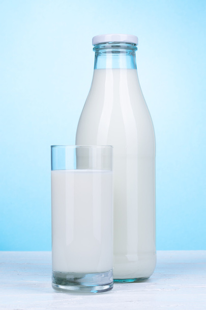 Fles en glas melk op lichte blauwe achtergrond. - Foto, afbeelding