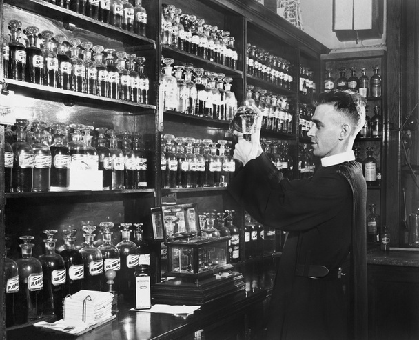 Mies apteekissa sekoittamassa lääkettä
 - Valokuva, kuva