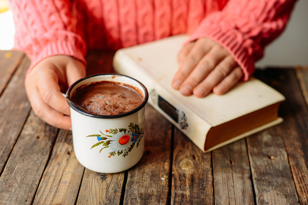 Vrouw met kopje warme chocolademelk. Warme chocolademelk in houten tabl - Foto, afbeelding