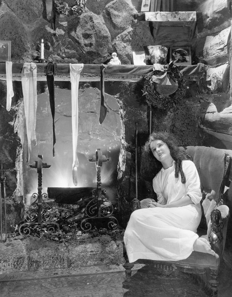 Fiatal nő ül a kandalló előtt szárítás a harisnya - Fotó, kép