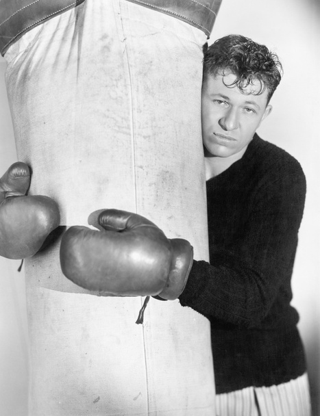 Man in boxing gloves hugging the punching bag - Photo, Image