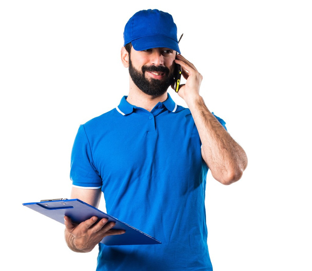 Delivery man with folder talking to mobile - Fotoğraf, Görsel