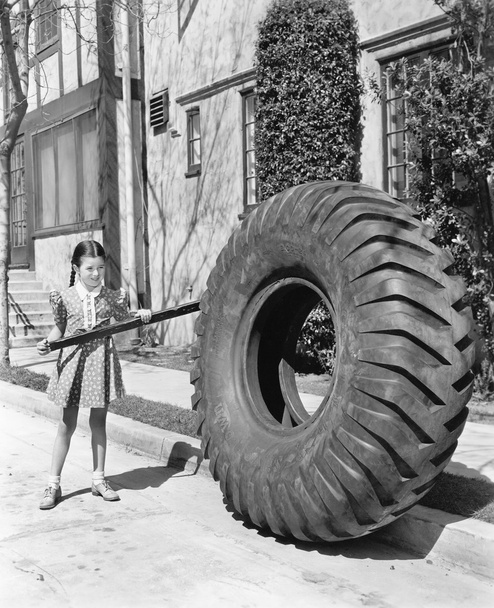 Girl playing with a huge tire and stick - Photo, Image
