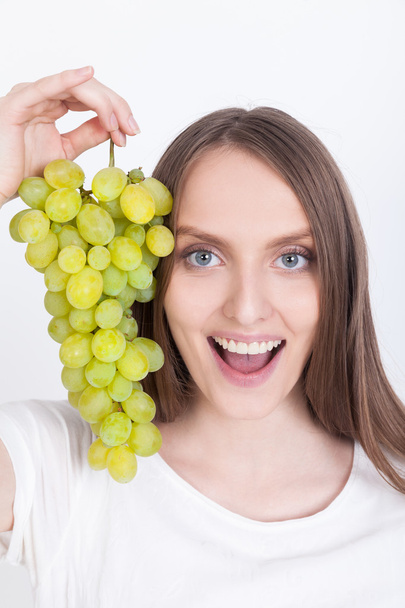 Smiling girl in white T-shirt with grapes - Foto, afbeelding