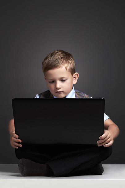 Niño con computadora. niño divertido mirando en el cuaderno. educación
 - Foto, imagen