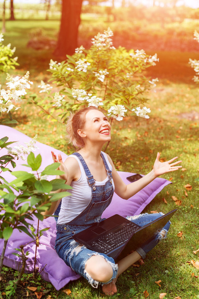 Freelancer working in the garden. Writing, surfing in the internet. Young woman relaxing and having fun in park area. Distance education, freelance concept. - Foto, imagen