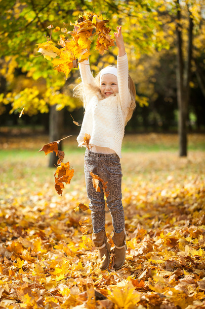 Young girl throwing leaves in autumn park - Фото, зображення