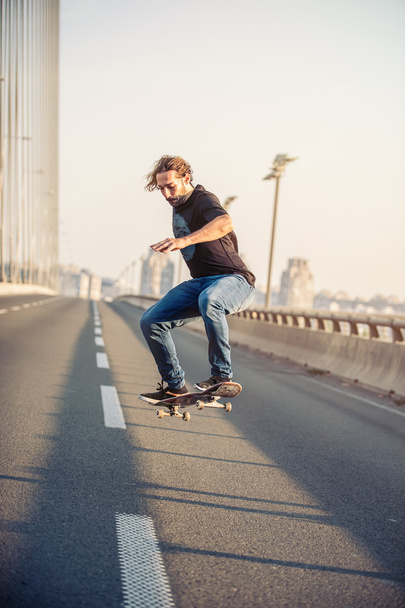 Skateboarder riding a skate and doing jumps on the road bridge - Photo, Image