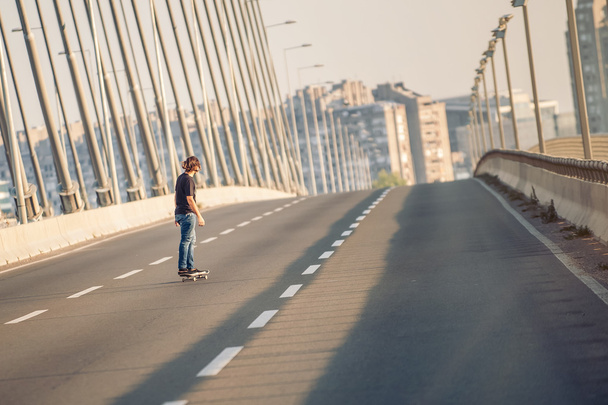 Skateboarder riding a skate over a city road bridge - Foto, imagen