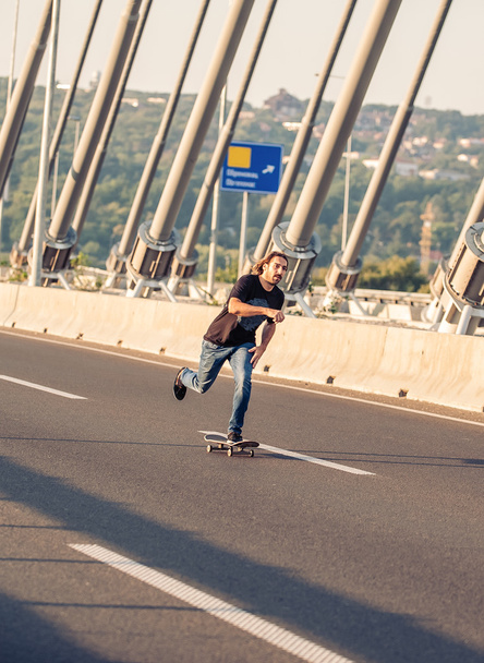 都市道路橋の上をスケートに乗ってのスケートボーダー - 写真・画像