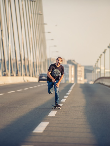 Skateboarder riding a skate over a city road bridge - Фото, изображение