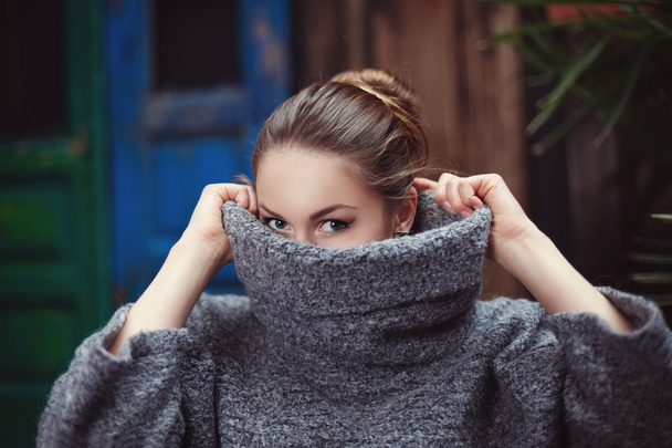 Egy fiatal nő kötött garbó pulóverben eltakarja az arcát. Közelről. - Fotó, kép