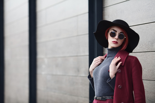 Closeup portrait of young beautiful fashionable woman with sunglasses. Lady posing on grey wooden background. Model wearing stylish wide-brimmed hat. Girl looking at camera. Female fashion. Copy space - Foto, imagen