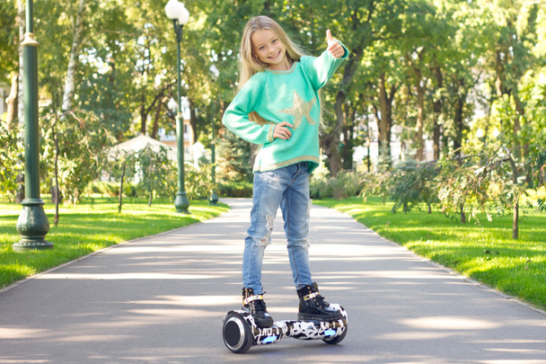 Маленька дівчинка їде на електричному скутері. Особистий екологічний транспорт, циганський скутер, розумне колесо балансу
. - Фото, зображення