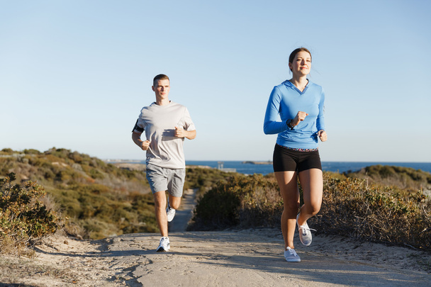 Urheilu juoksija lenkkeily rannalla treenata hänen kumppaninsa kanssa
 - Valokuva, kuva