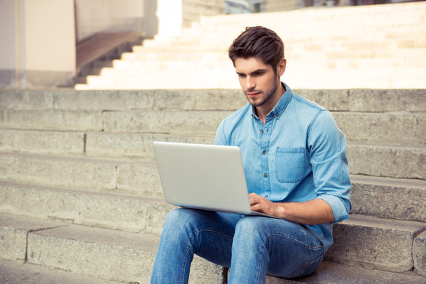 handsome young man sitting on the stairs and work with laptop - Zdjęcie, obraz