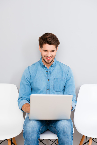 Happy young man sitting on chair and working with laptop - Φωτογραφία, εικόνα