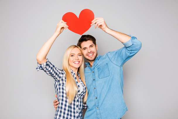 Portrait of two happy people holding red paper heart under head - Foto, immagini