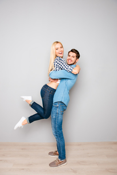 Handsome young man carrying his pretty girlfriend - Foto, afbeelding