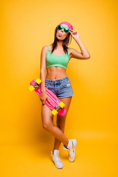 Full height of funny hipster girl showing tongue with pink longb - Fotoğraf, Görsel