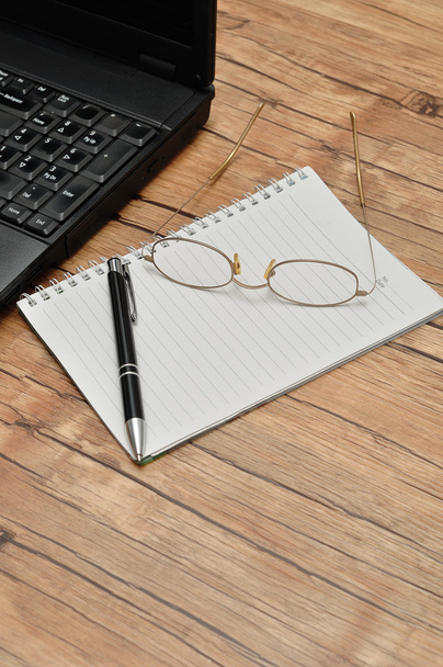 Egy laptop-val olvasó szemüveg, egy tollat és egy jegyzet könyv - Fotó, kép